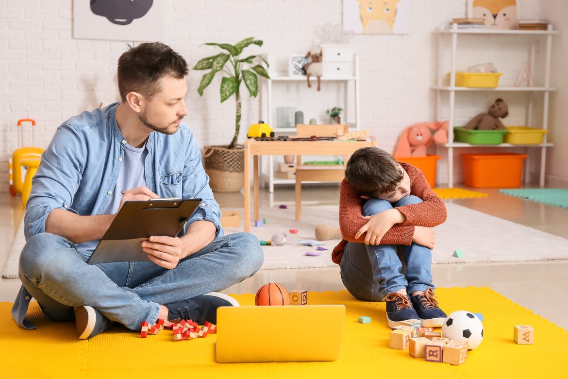 Male psychologist working with little boy in office. Autism concept